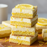 A stack of lemon cream cheese brownies showing their golden base and creamy lemon layer.