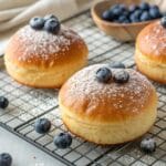 Freshly baked blueberry and custard brioche buns dusted with powdered sugar.